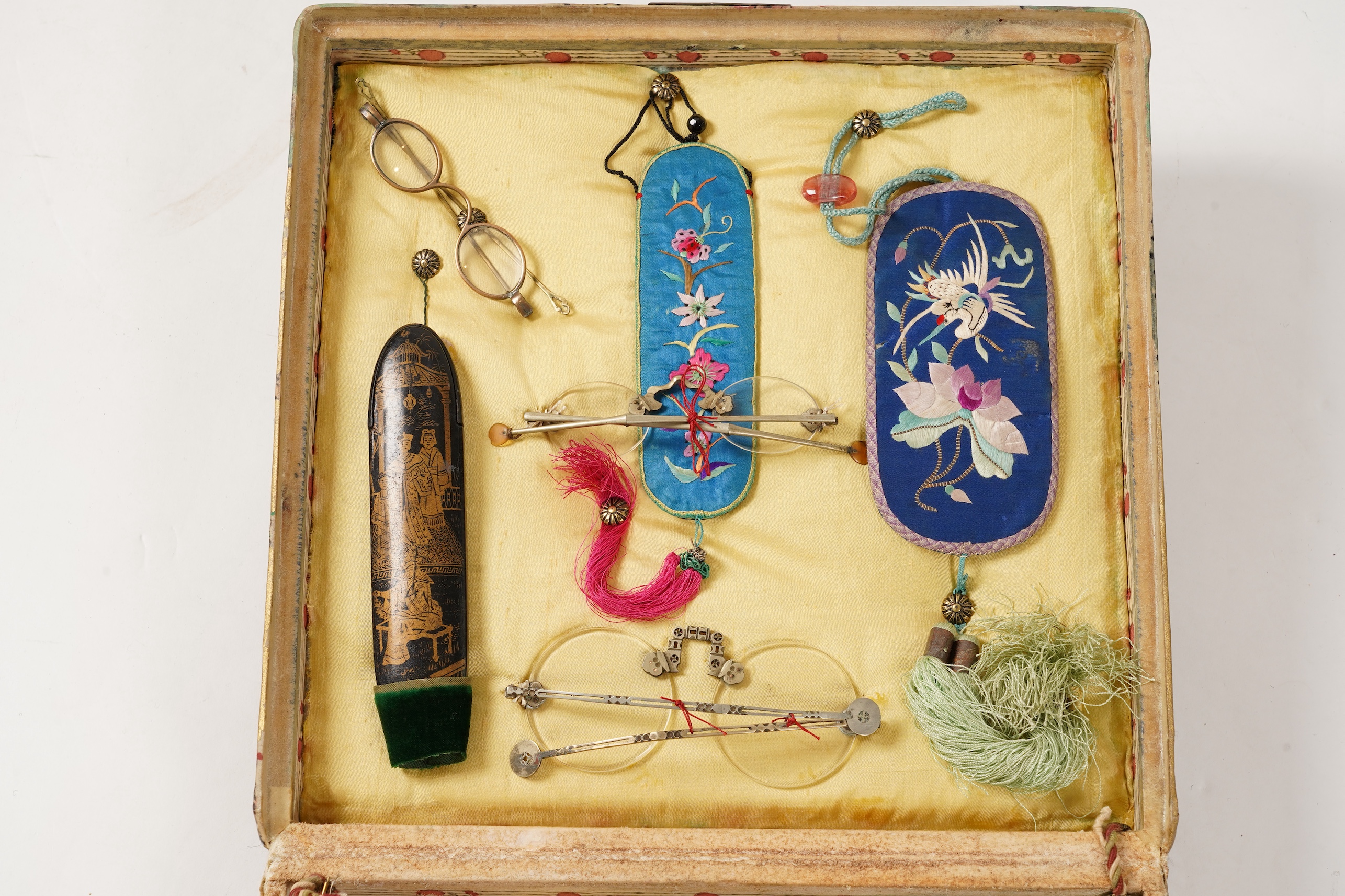 A collection of 19th/20th century Chinese embroidered silk spectacle cases and various spectacles, Box 33cm square